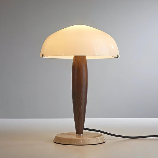 Marble base table lamp lit and seen from the front on a pale ground