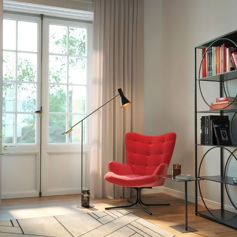 The lit lamp beside a red armchair with a bookcase and a glazed door behind