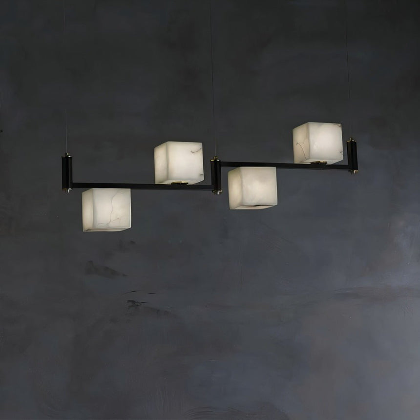 Four lit alabaster cubes in a row on a slim black bar below a plate