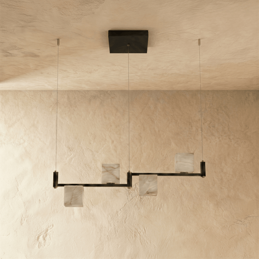 The same three alabaster cubes unlit, pale stone against a plaster wall
