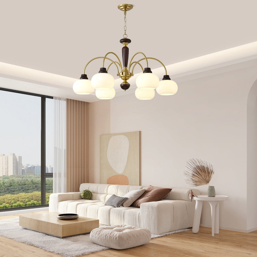 Chandelier lit in a pale room above a sofa and a wide window