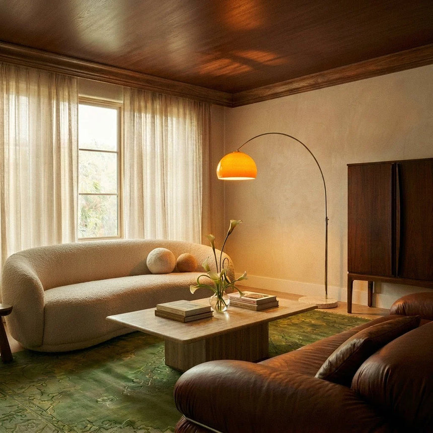 The orange dome lit over a curved sofa in a living room with curtains and a low table