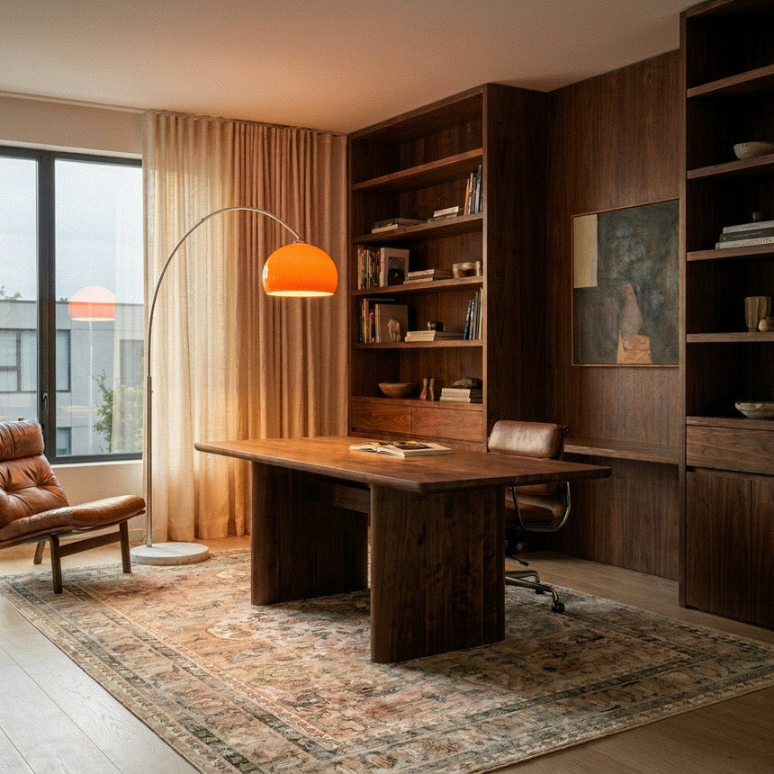 The orange dome lit over a timber desk in an office with a bookcase and a rug
