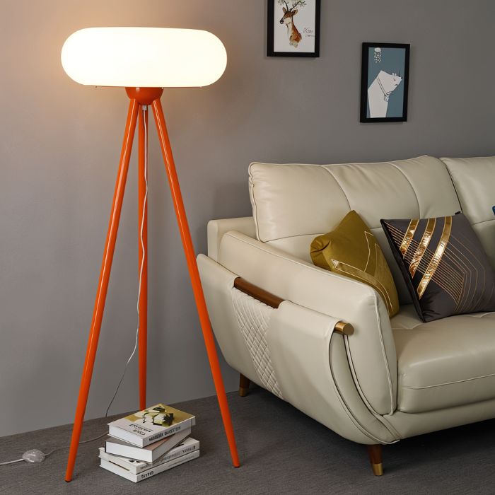 The orange lamp lit beside a cream sofa with cushions, framed pictures behind