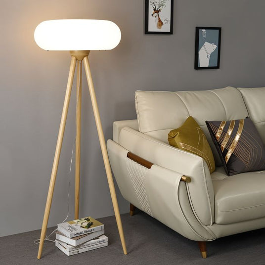 The natural wood lamp lit beside a cream sofa with cushions, artwork and books