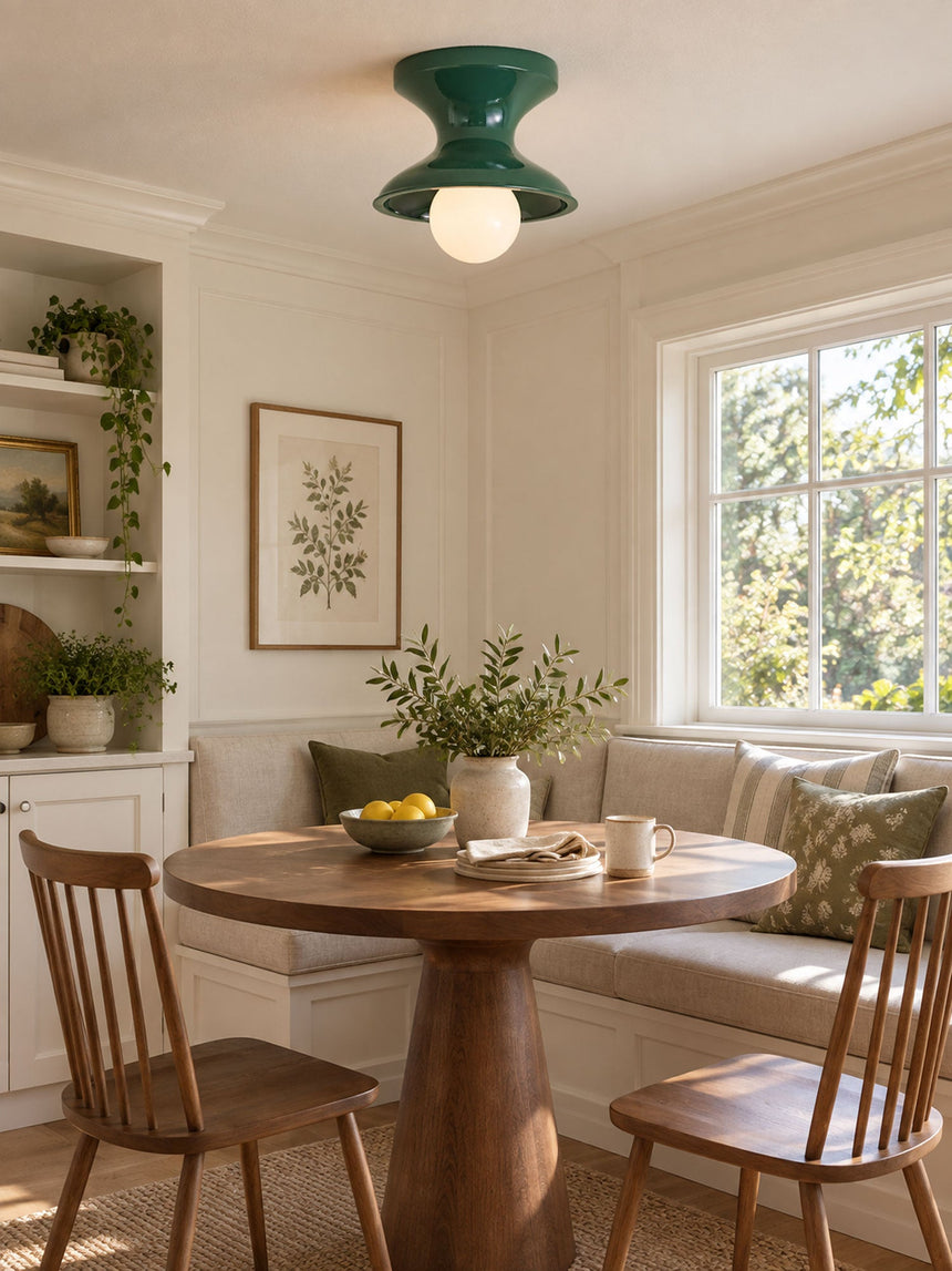 Green spool ceiling light in a dining nook with a round wood table