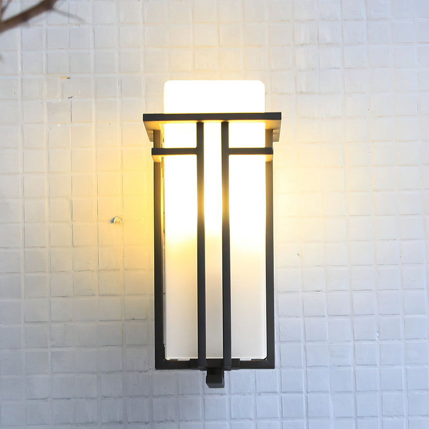 The lantern lit on a white tiled wall, the black bars crossing the glass
