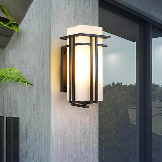 The lantern lit on a gray wall beside a large window, a fern leaf in the corner