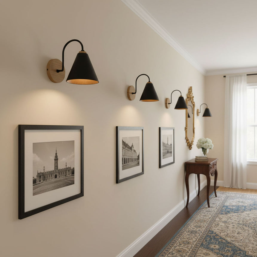 Three sconces lit along a hallway wall above framed prints and a console