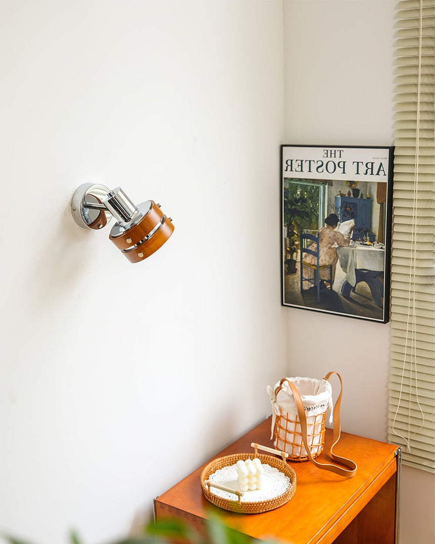 Sconce lit above a console holding glassware beside a framed poster