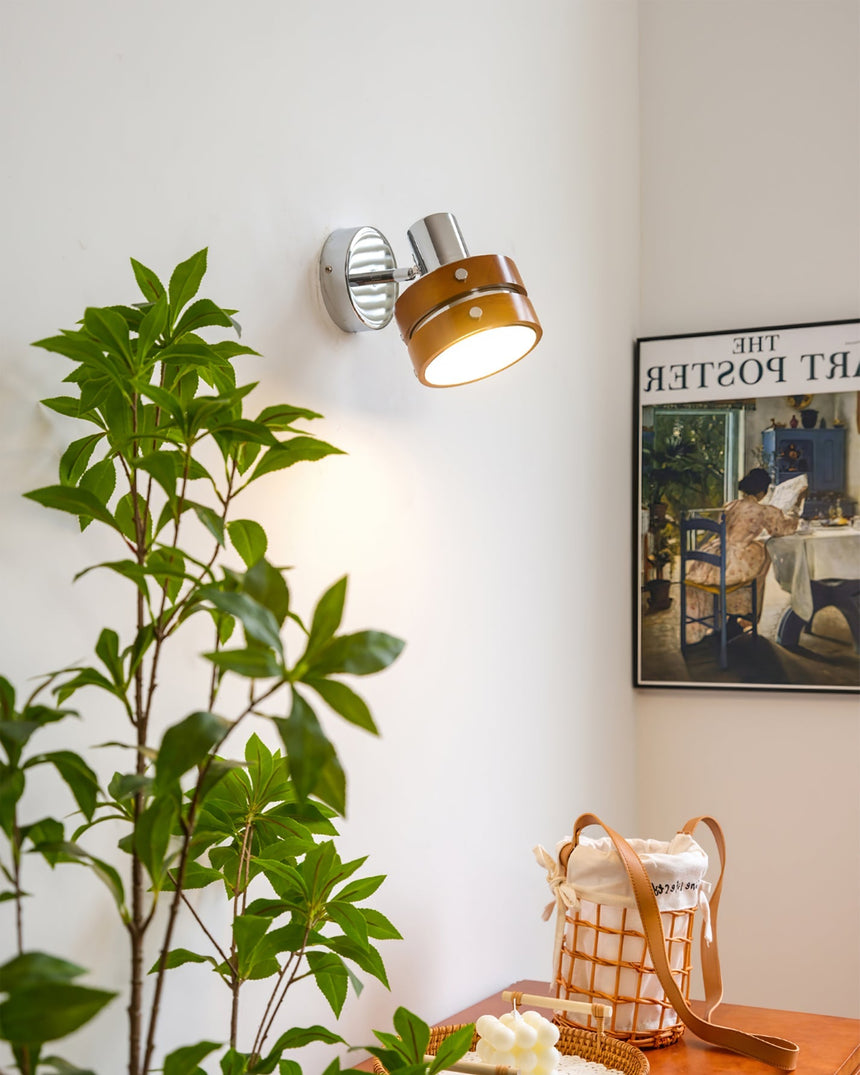 Sconce lit in a corner beside a tall plant and a framed poster on the wall