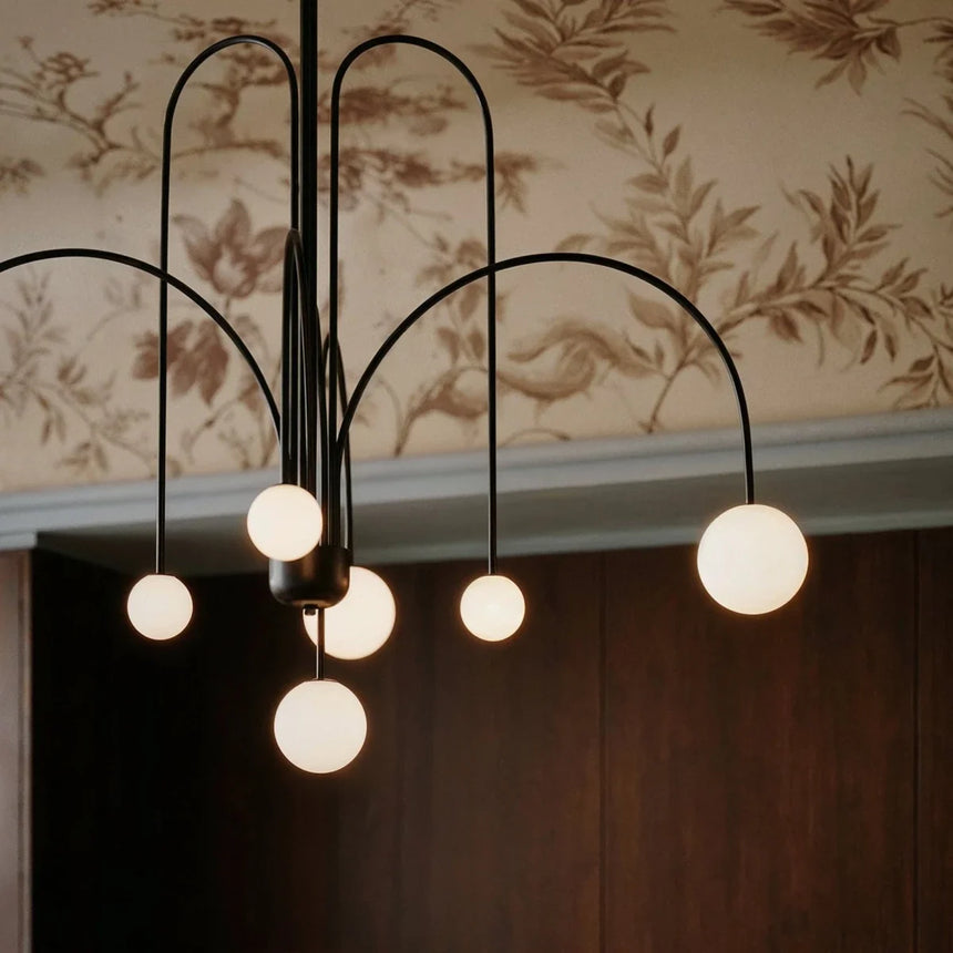 The black arms and their lit globes seen against patterned botanical wallpaper