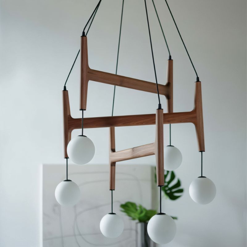 The walnut frame and its globes seen against a pale wall with foliage nearby