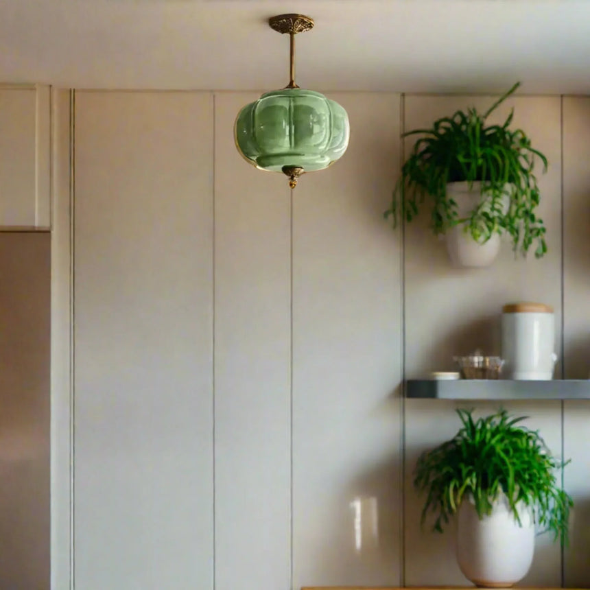 Green ribbed shade beside a pale paneled wall with shelves and plants