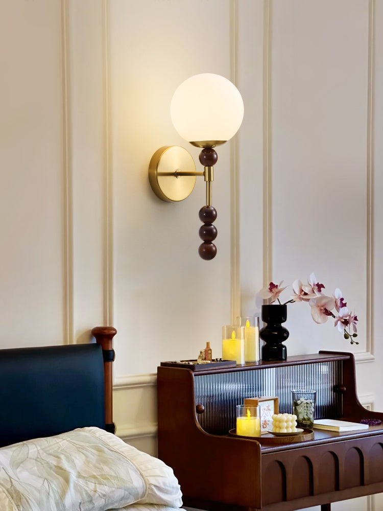 Milk glass globe lit above a glass fronted cabinet holding lit candles