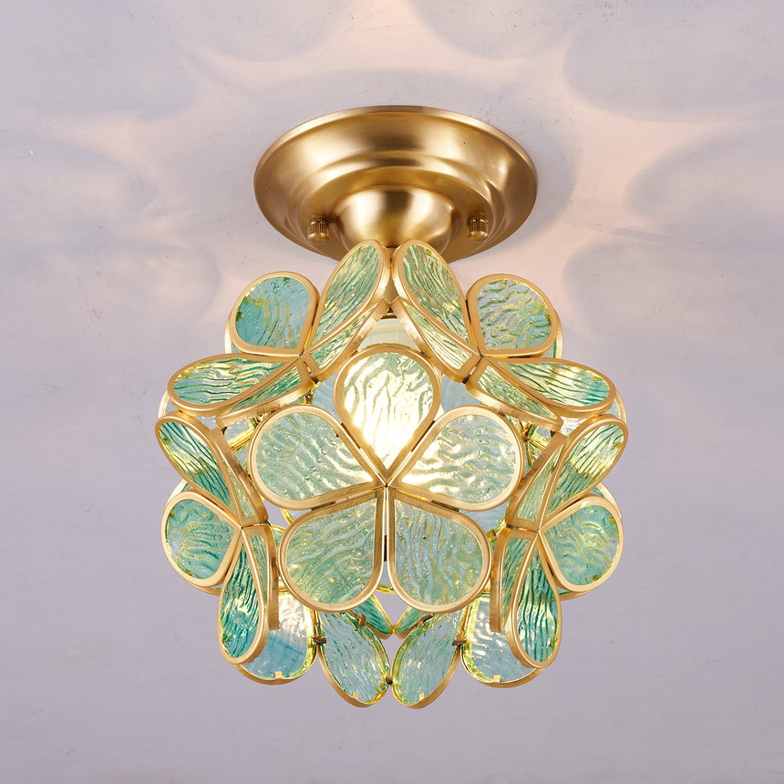 Green glass petal ceiling light lit on a plain ceiling