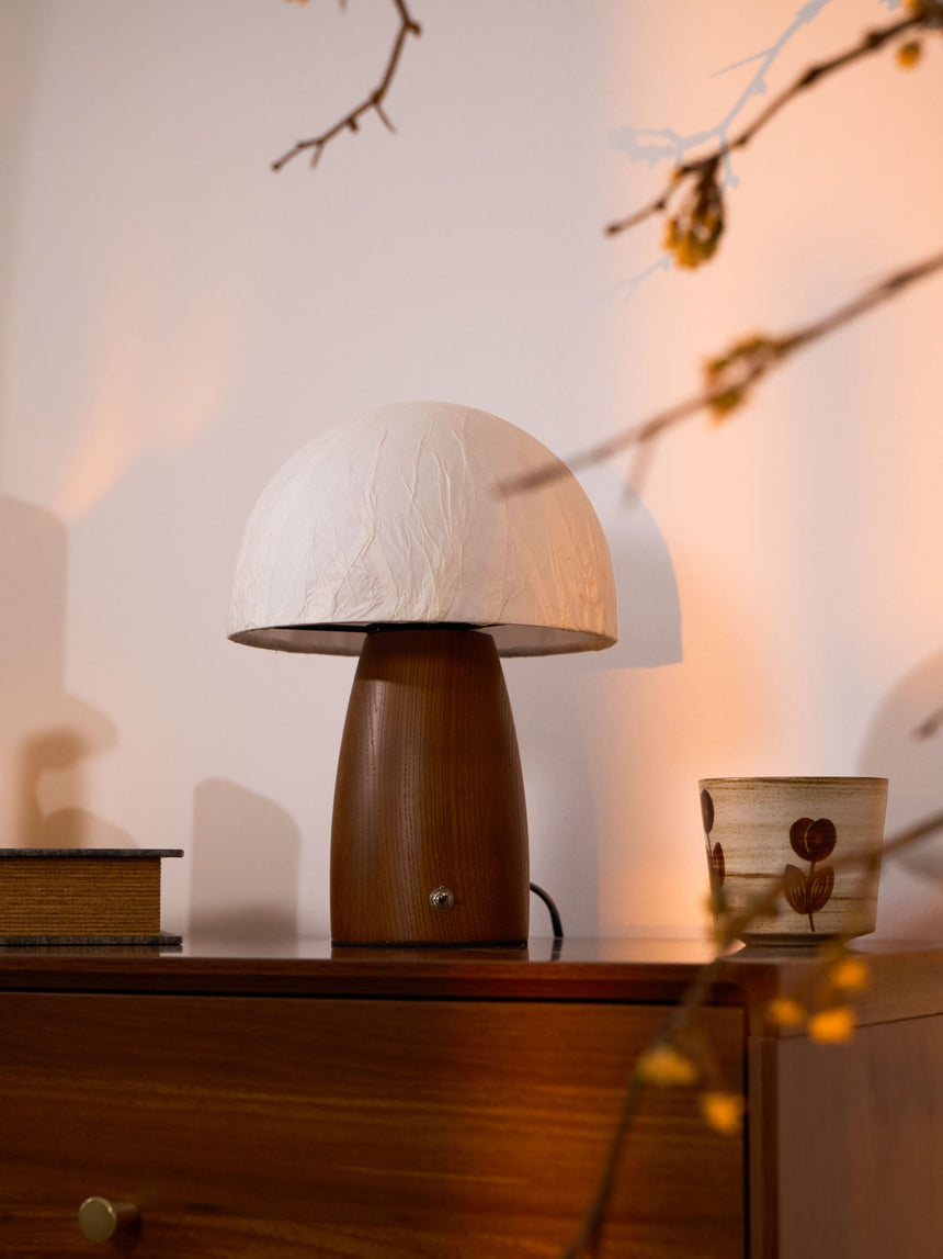 Mini table lamp on a wooden chest with a branch and a cup beside it