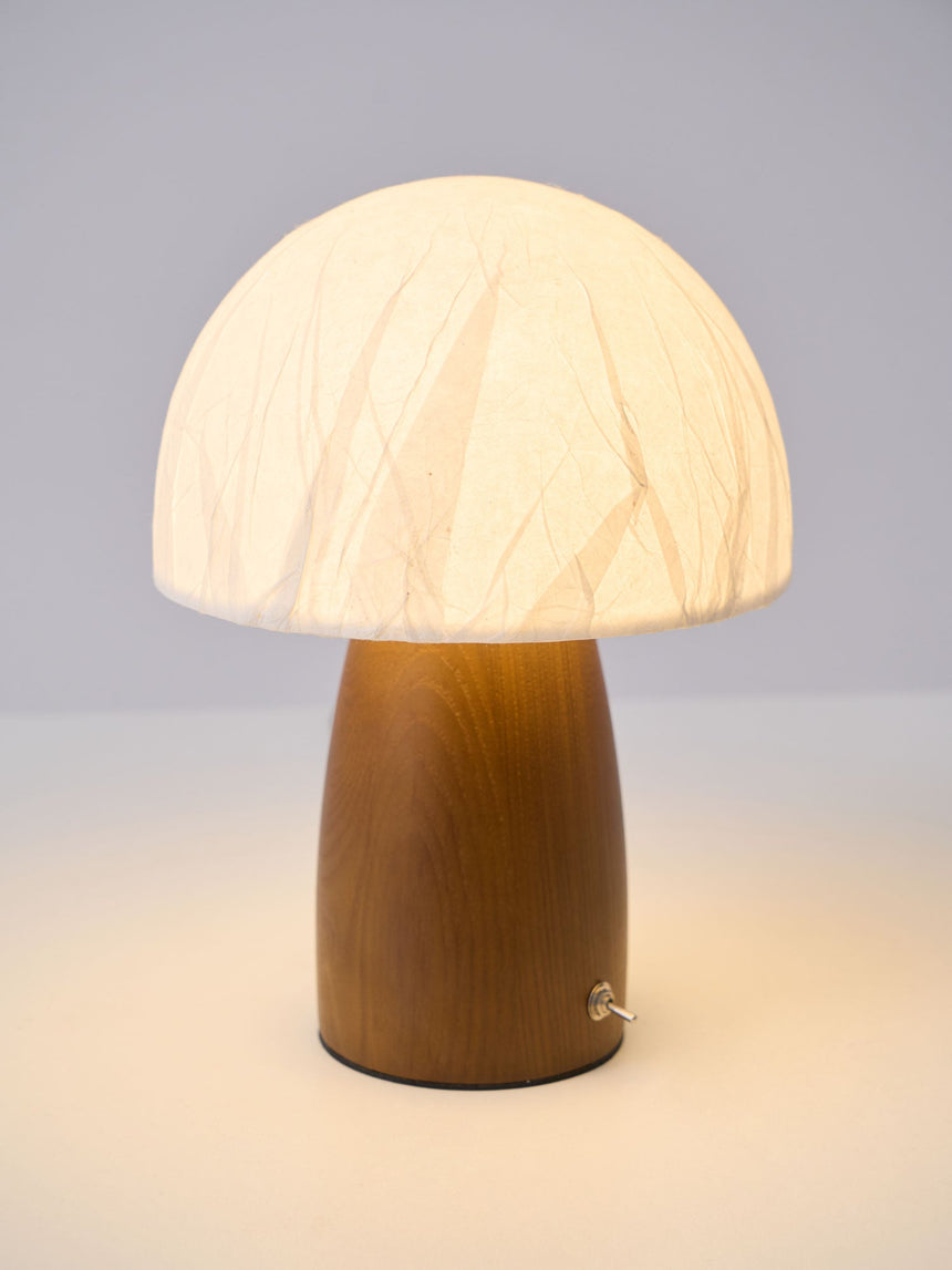Mini table lamp switched on against a plain pale background