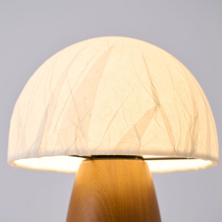 Close view of the crinkled paper dome lit from inside above the wood base