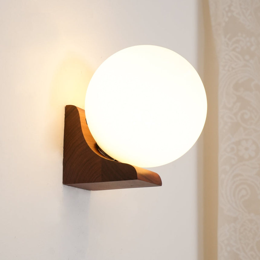 Sconce lit beside a patterned curtain, warm light on the wall around it