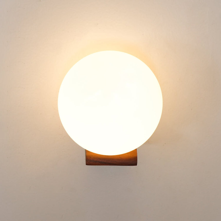 The sphere lit bright, warm light spilling onto the wall around it