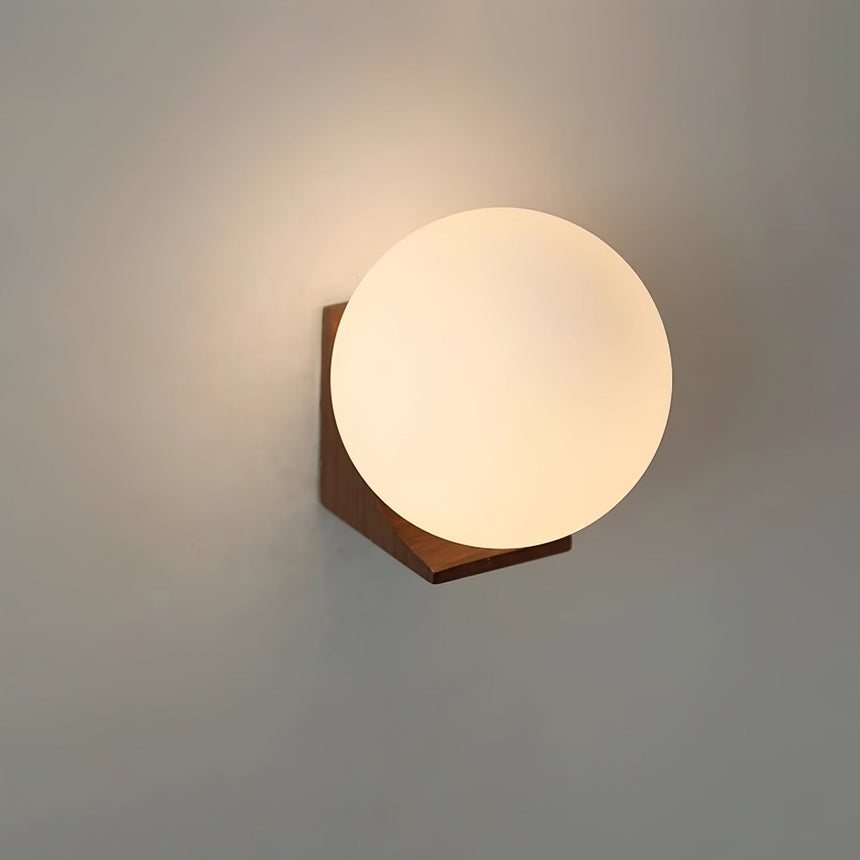 The walnut bracket and sphere lit warm against a plain pale wall