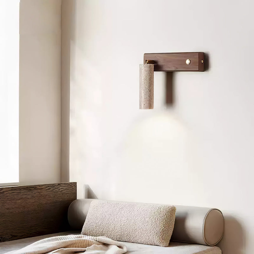 Sconce lit above a bed with a bolster, the beam washing the wall above