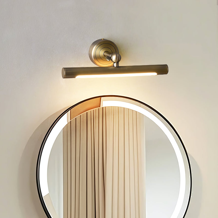 Bronze bar lit over a round mirror reflecting a curtain, the glow filling the glass