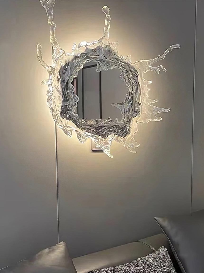 The mirrored light glowing on a gray wall above the corner of a sofa