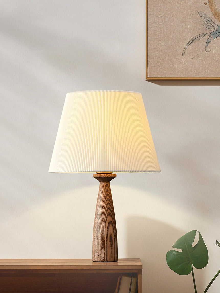 Ribbed shade lamp on a shelf in sunlight beside a small green plant
