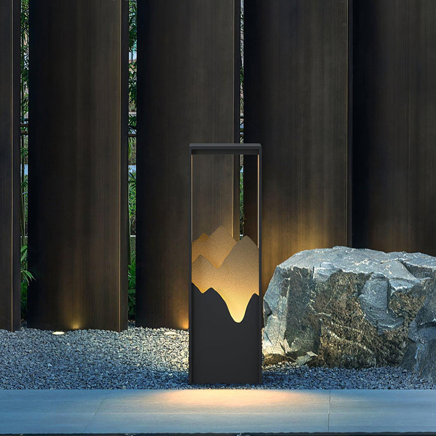 The bollard lit beside a pale stone at the edge of shallow water