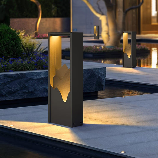 Two lit on paving beside a water feature with planting behind them