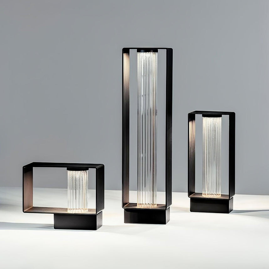 The three sizes lit together on a pale floor beside a studio wall