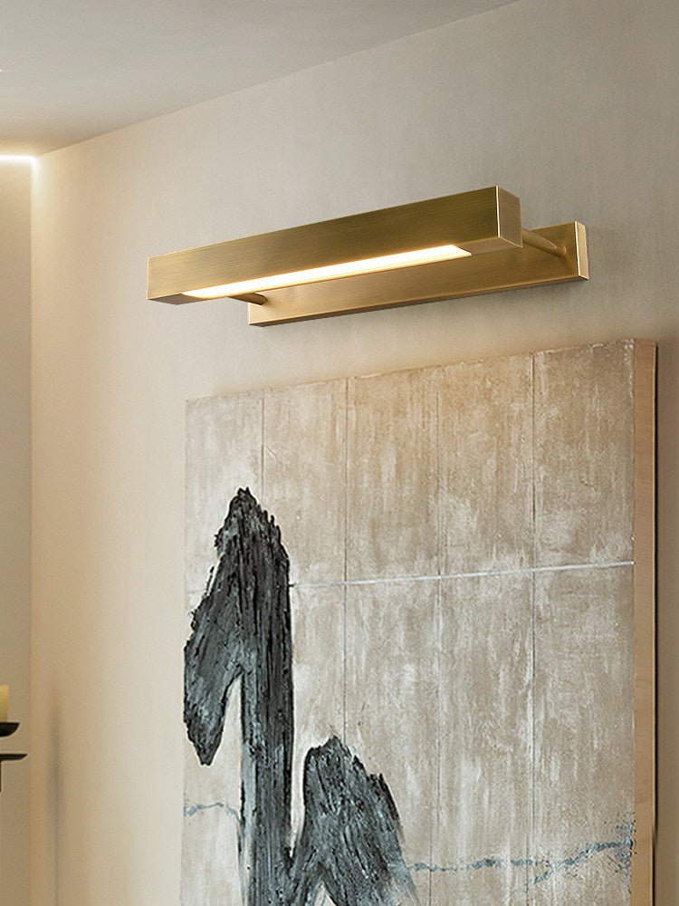 Brass bar lit over a wide textured canvas on a pale wall in a quiet room