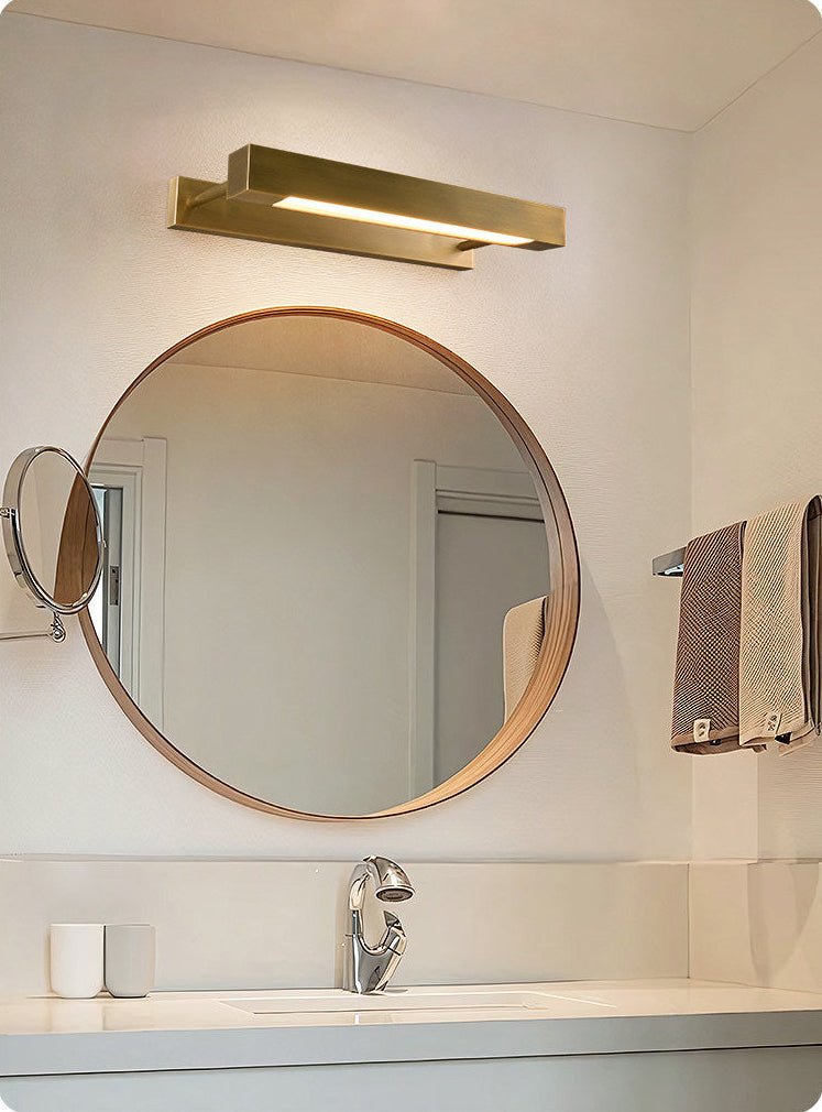 Brass bar above a round mirror over a basin with a folded towel nearby