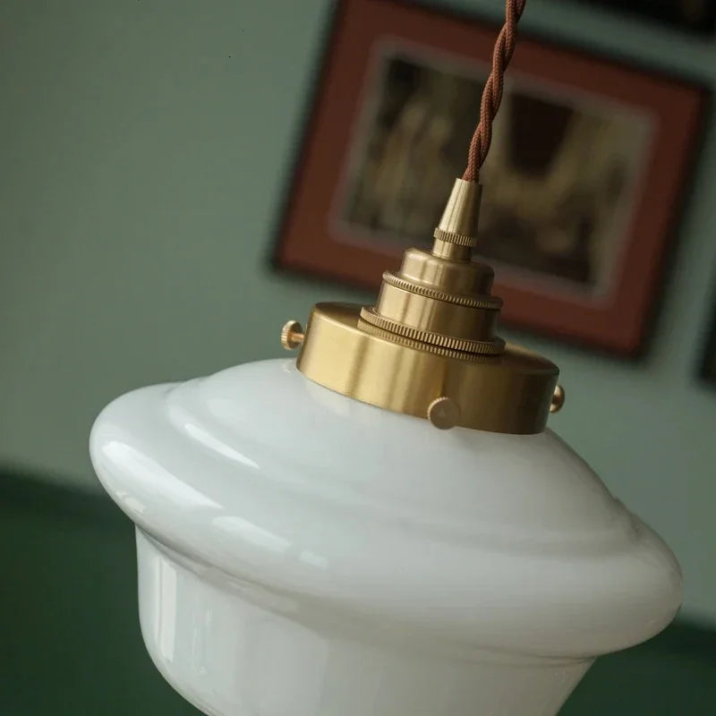 Close view of the knurled brass socket holding the opal shade below a framed picture