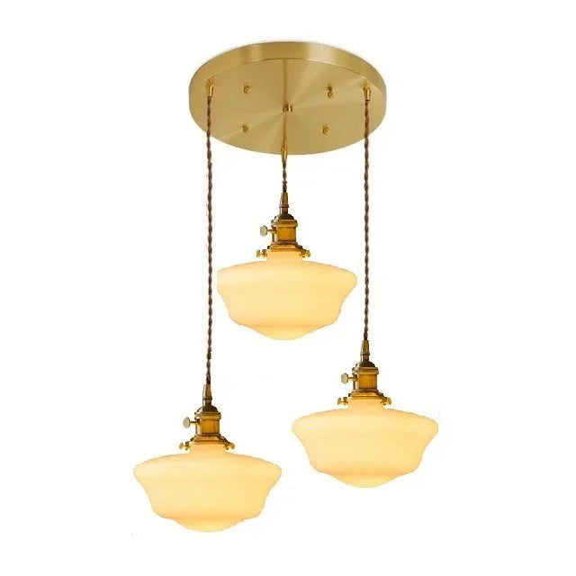 Three opal shades hung close together from one round brass ceiling plate