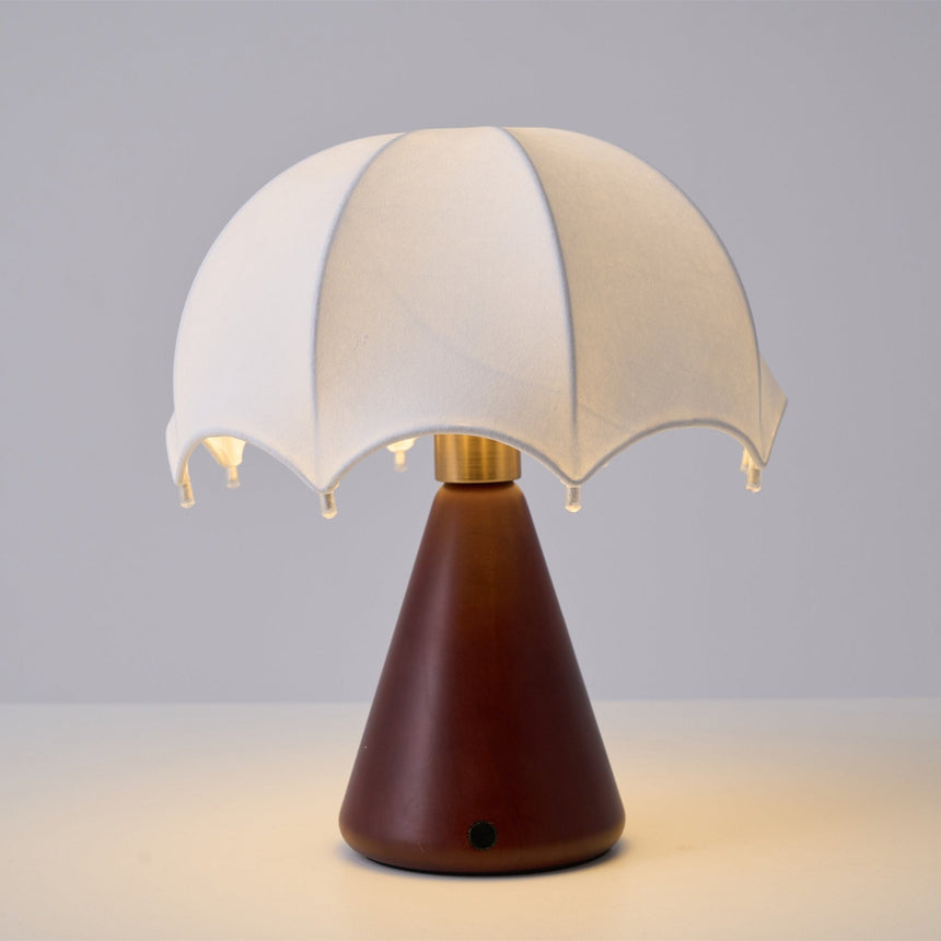 Nightstand lamp lit against a plain ground, the silk glowing