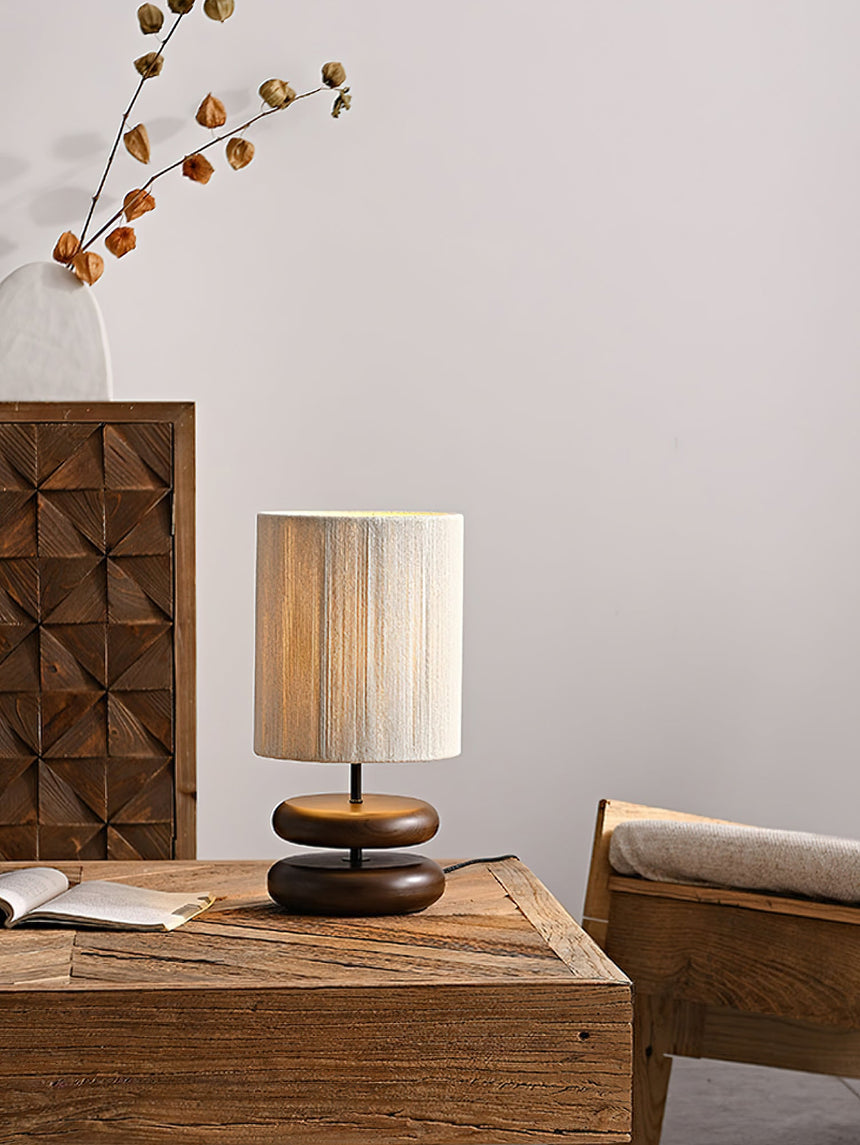 Nightstand table lamp lit on a bedside table in a pale room