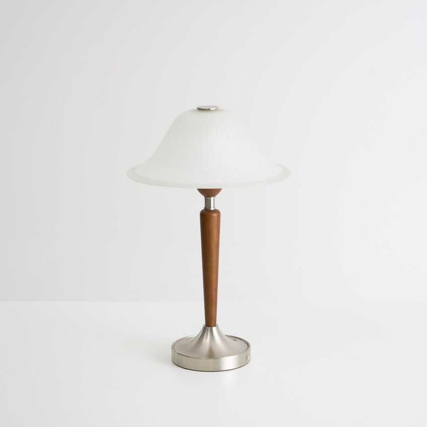 Nightstand table lamp seen from the front against a plain pale ground