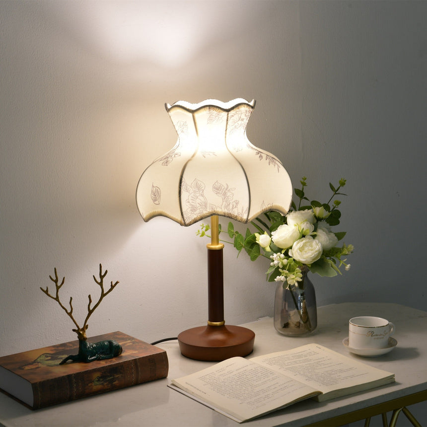 Blossom shade lamp lit on a desk beside a bonsai and an open book