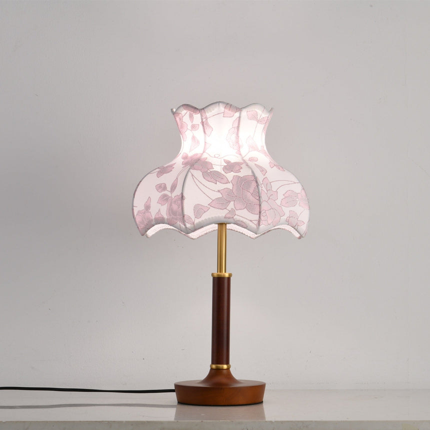 Pink blossom shade lamp on a plain ground with a wood disc base