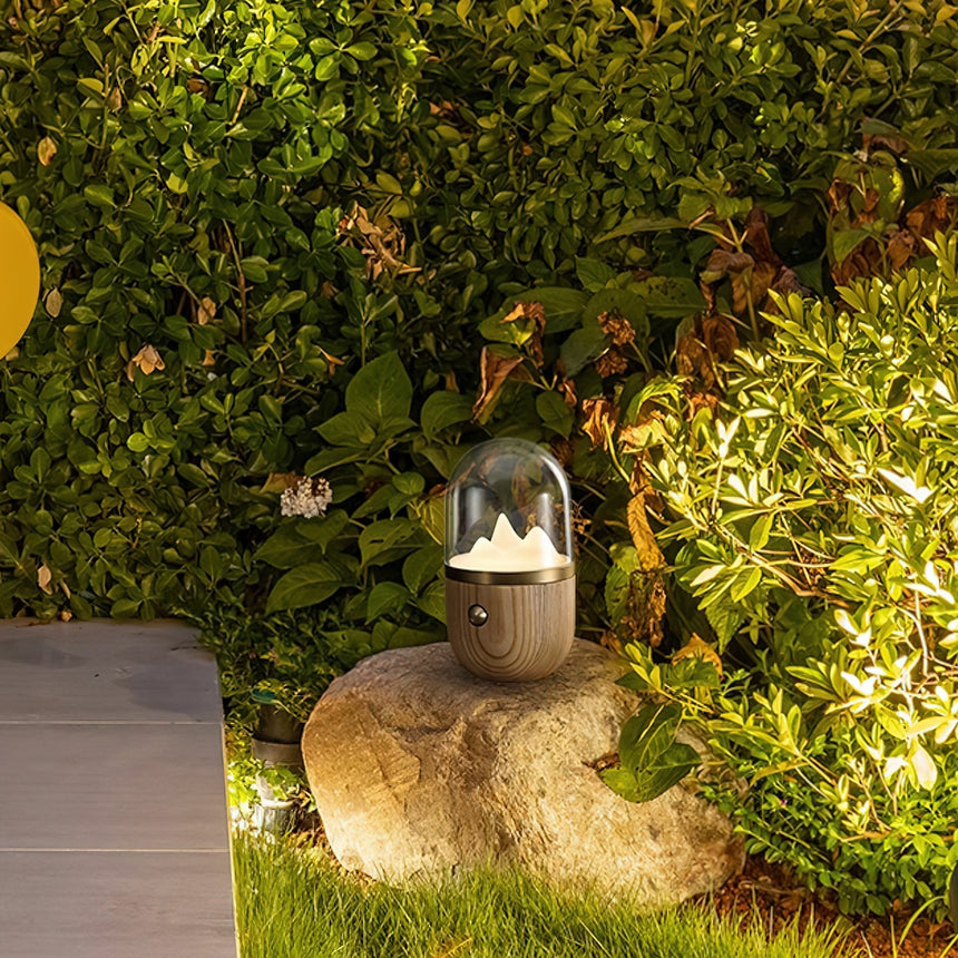 Nursery table lamp lit on a stone outdoors in front of green foliage