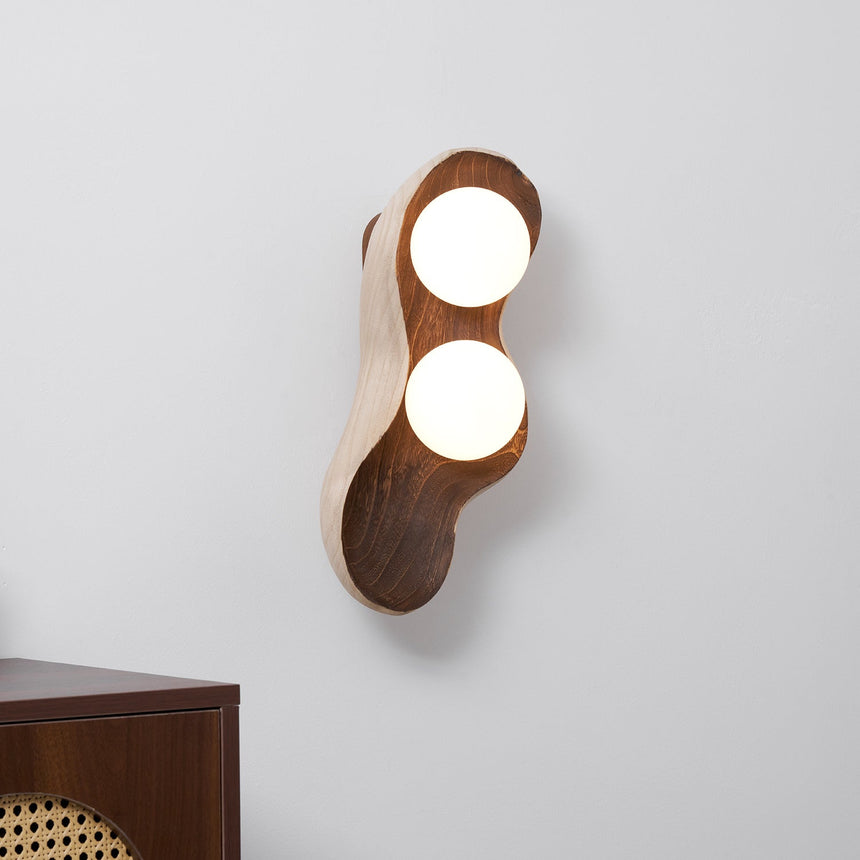 Sconce lit beside a cane fronted cabinet against a pale plaster wall