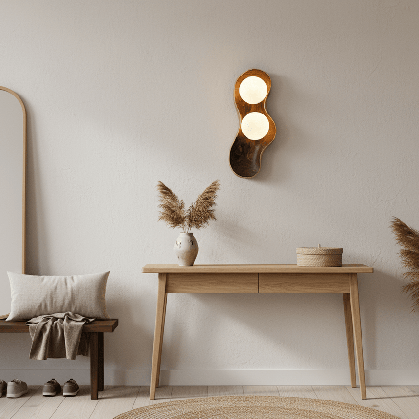 Sconce lit above an entry table with dried stems in a tall vase