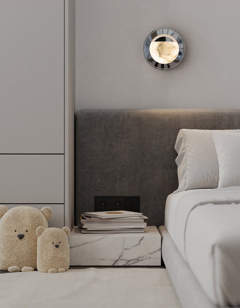 The orbit light lit above a bed with a gray headboard and a marble nightstand