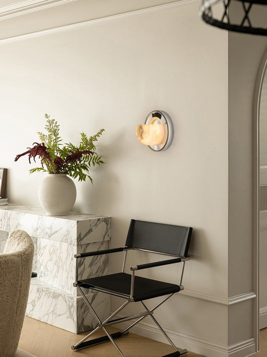 The orbit light lit above a leather chair beside a stone console with a vase