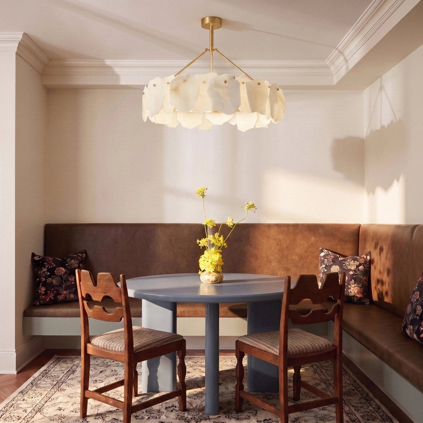 A petal ring lit above a dining table and a leather banquette