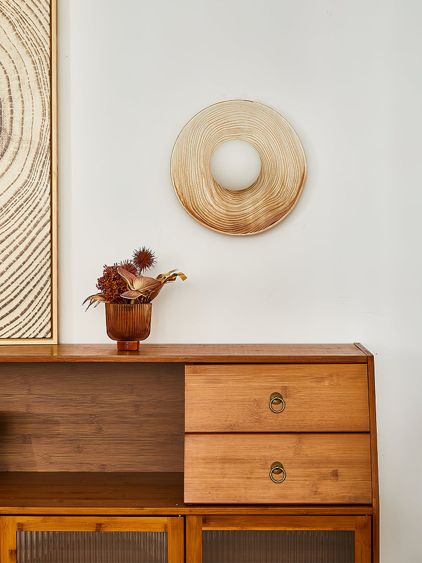 The sconce above a teak cabinet with drawers and a caned door