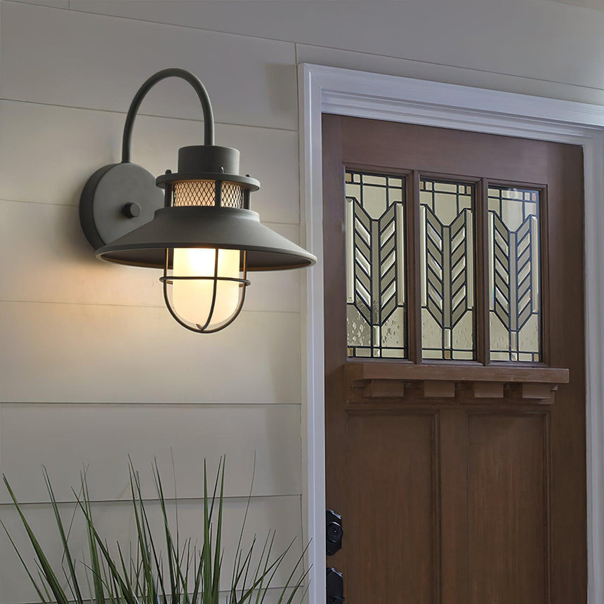 The light beside a paneled front door with grasses in a border